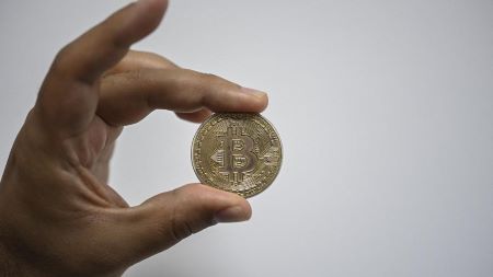 Un homme montre une pièce souvenir représentant un bitcoin