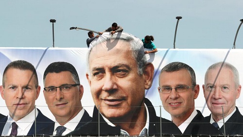 Des ouvriers mettent en place une bannière de la campagne du Likoud, le 28 mars à Jérusalem, pour les législatives du 9 avril prochain. REUTERS/Ammar Awad