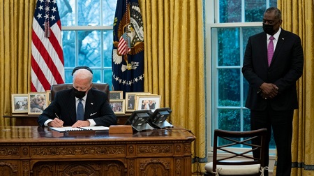 Le secrétaire américain à la Défense, Lloyd Austin, regarde le président Joe Biden signer un décret annulant l’interdiction d’une directive de l’ère Trump, le 25 janvier 2021. © AP