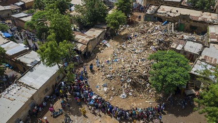 Des habitants du quartier se rassemblent autour des débris et ruines d'un immeuble qui s'est effondré à Bamako, tuant 15 personnes. © MICHELE CATTANI / AFP